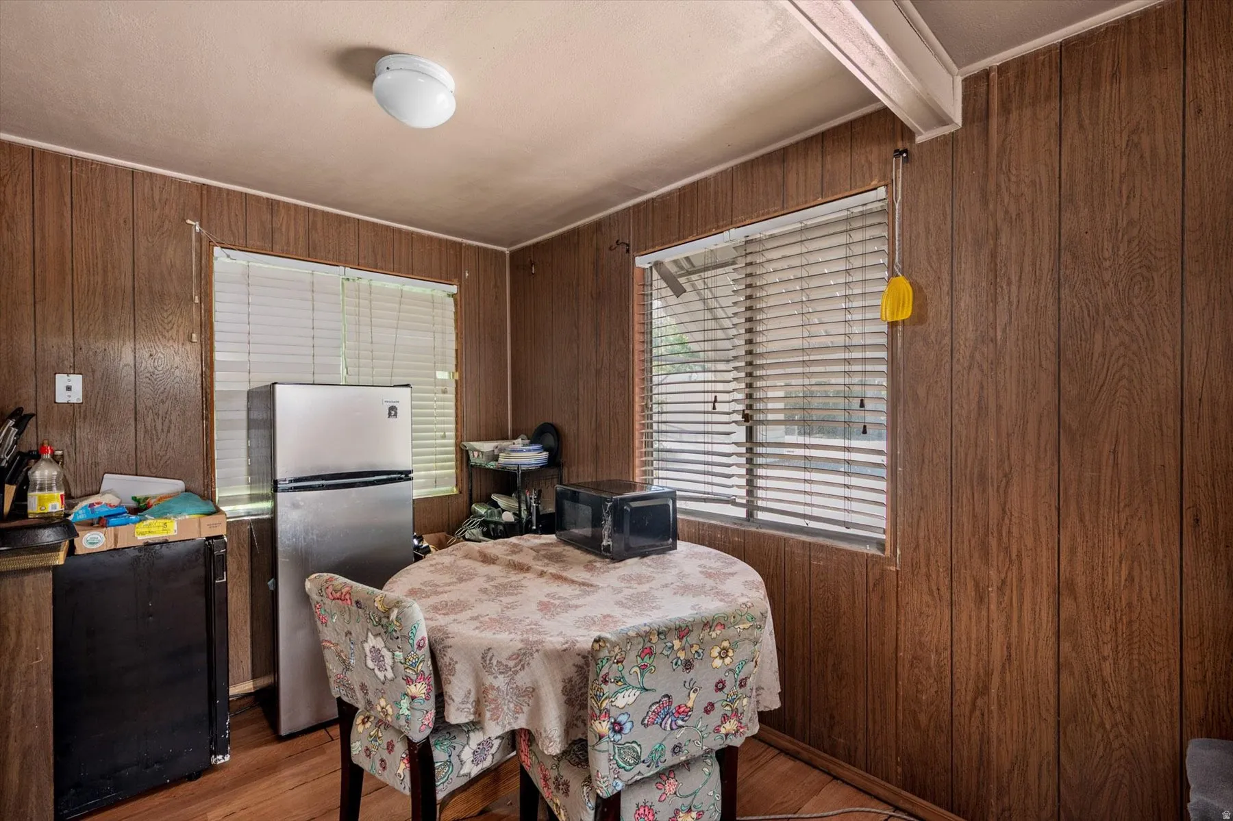 Kitchenette featuring wood-panel walls, wood-finish flooring, and a flush-mount ceiling light