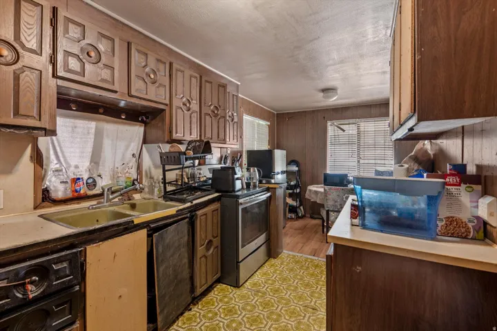 Kitchen area featuring wood-paneled walls and a window with blinds