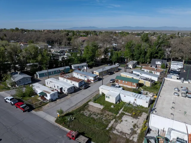 Aerial perspective showcasing a mobile home community with multiple units, paved roadways, and surrounding mature trees