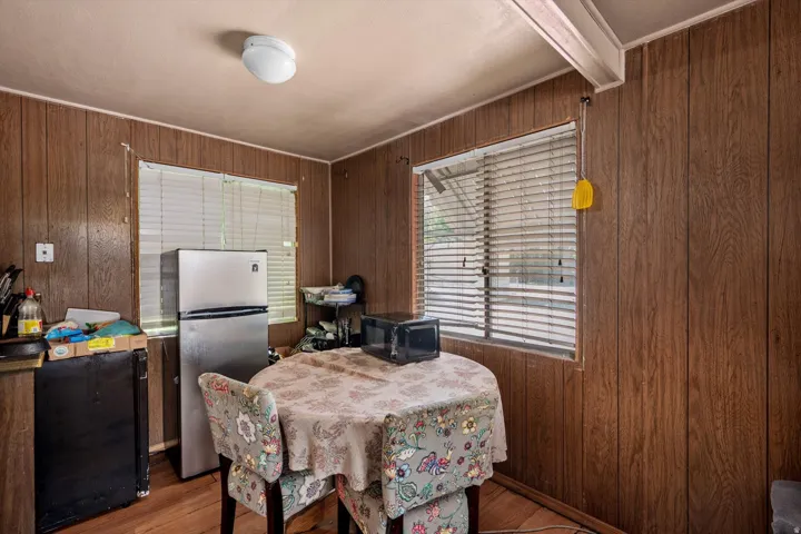 Kitchenette featuring wood-panel walls, wood-finish flooring, and a flush-mount ceiling light