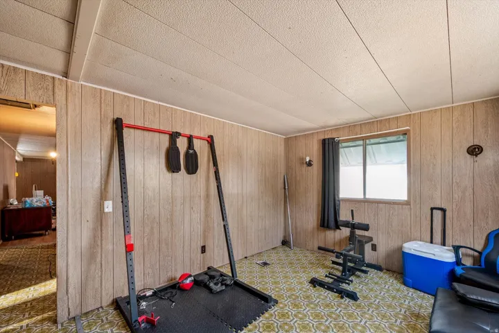 Room featuring wood-finish paneling, patterned flooring, a white window, and a textured ceiling