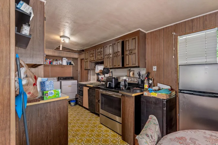 Kitchen featuring wood-panel walls, patterned linoleum flooring, and built-in wood cabinetry