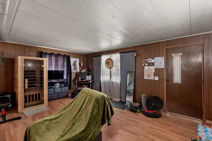 Room featuring wood-finish flooring, wood paneling, and a textured ceiling