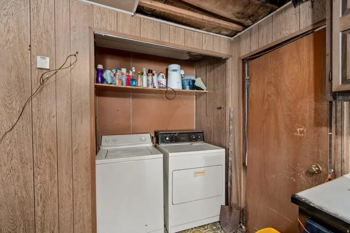 Dedicated laundry area featuring a washer and dryer hookup, wood paneling, and an overhead storage shelf