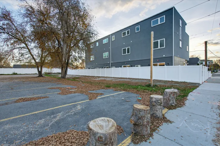 Paved parking area with painted space markers, bordered by a white privacy fence