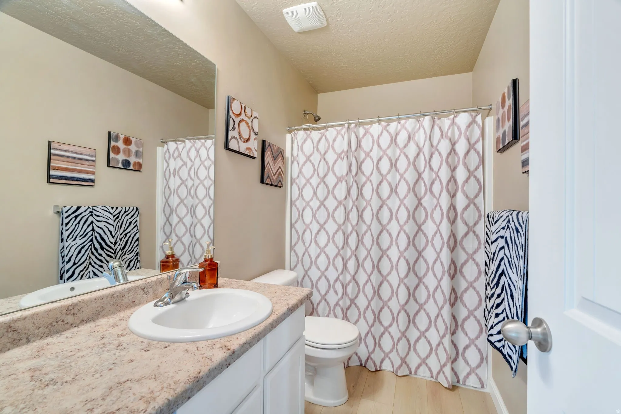Bathroom featuring a vanity with a light-toned countertop, integrated sink, and white cabinetry