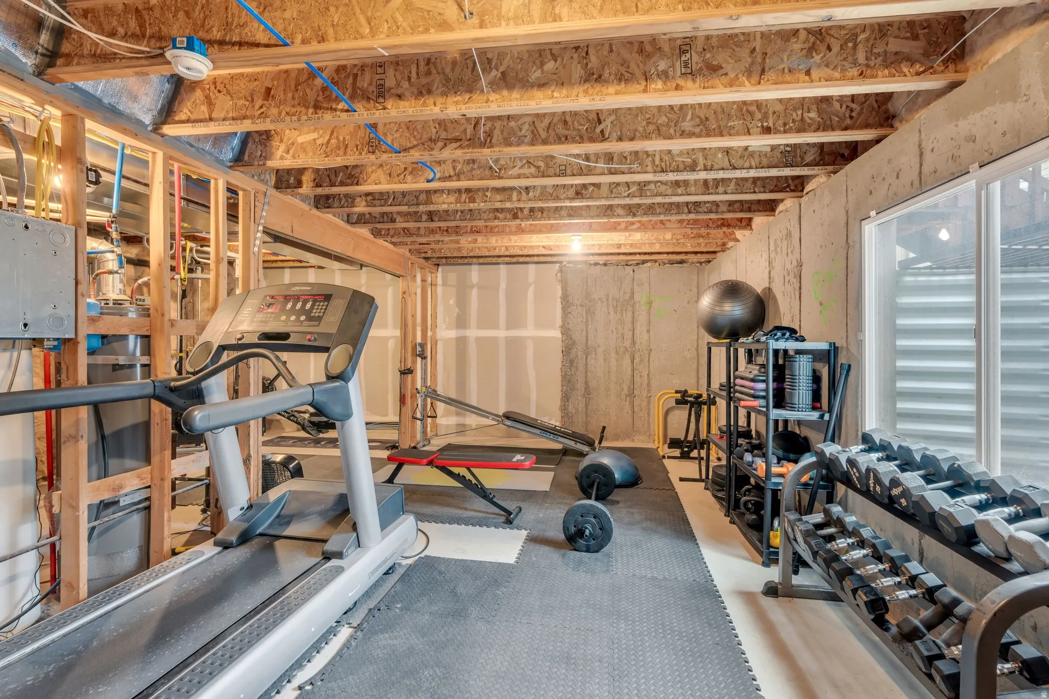 Unfinished basement offering flexible utility space with exposed wood framing, concrete foundation walls, and an egress window