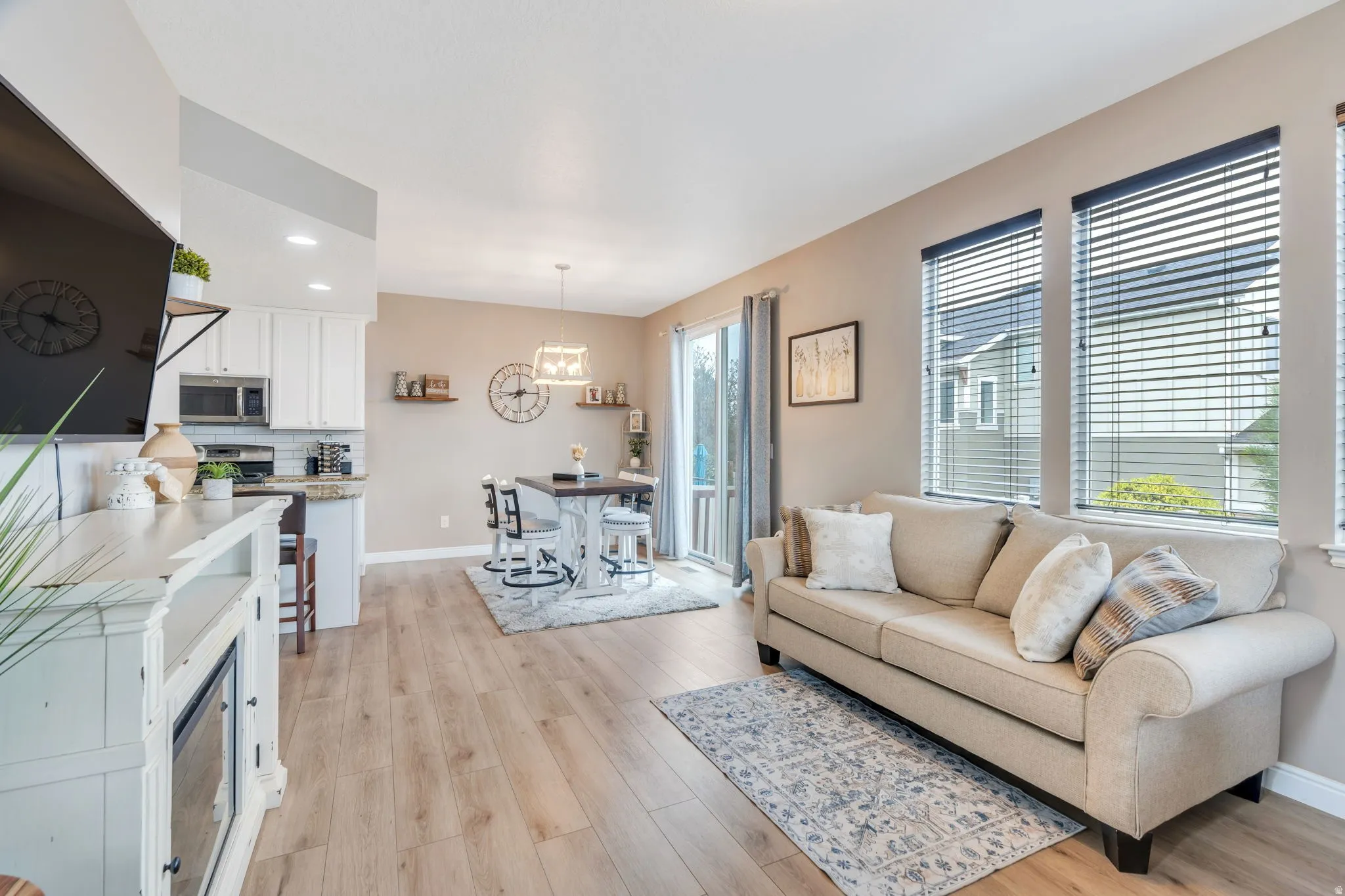 Open-concept living space featuring wood-finish flooring, recessed lighting, and multiple windows with blinds