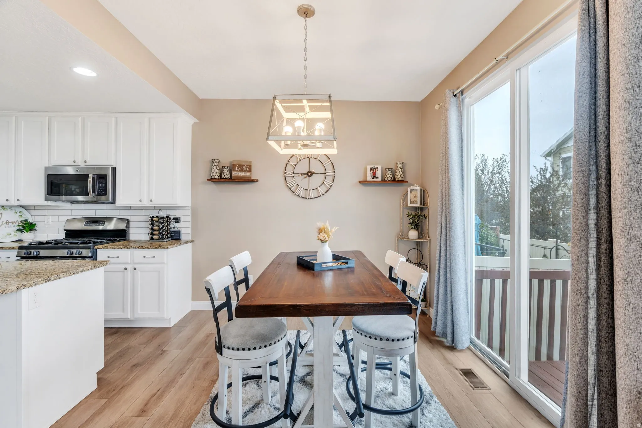 Open-concept kitchen and dining area featuring wood-finish flooring, white cabinetry, a granite-finish island, and stainless steel appliances