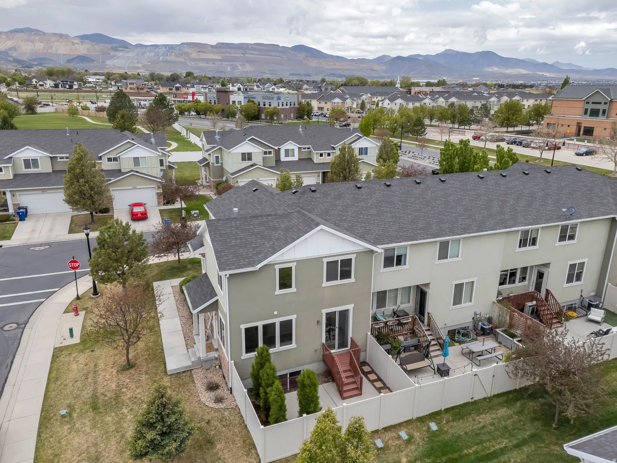 Townhome residence with a neutral-toned stucco exterior, white trim, and a dark gray shingle roof