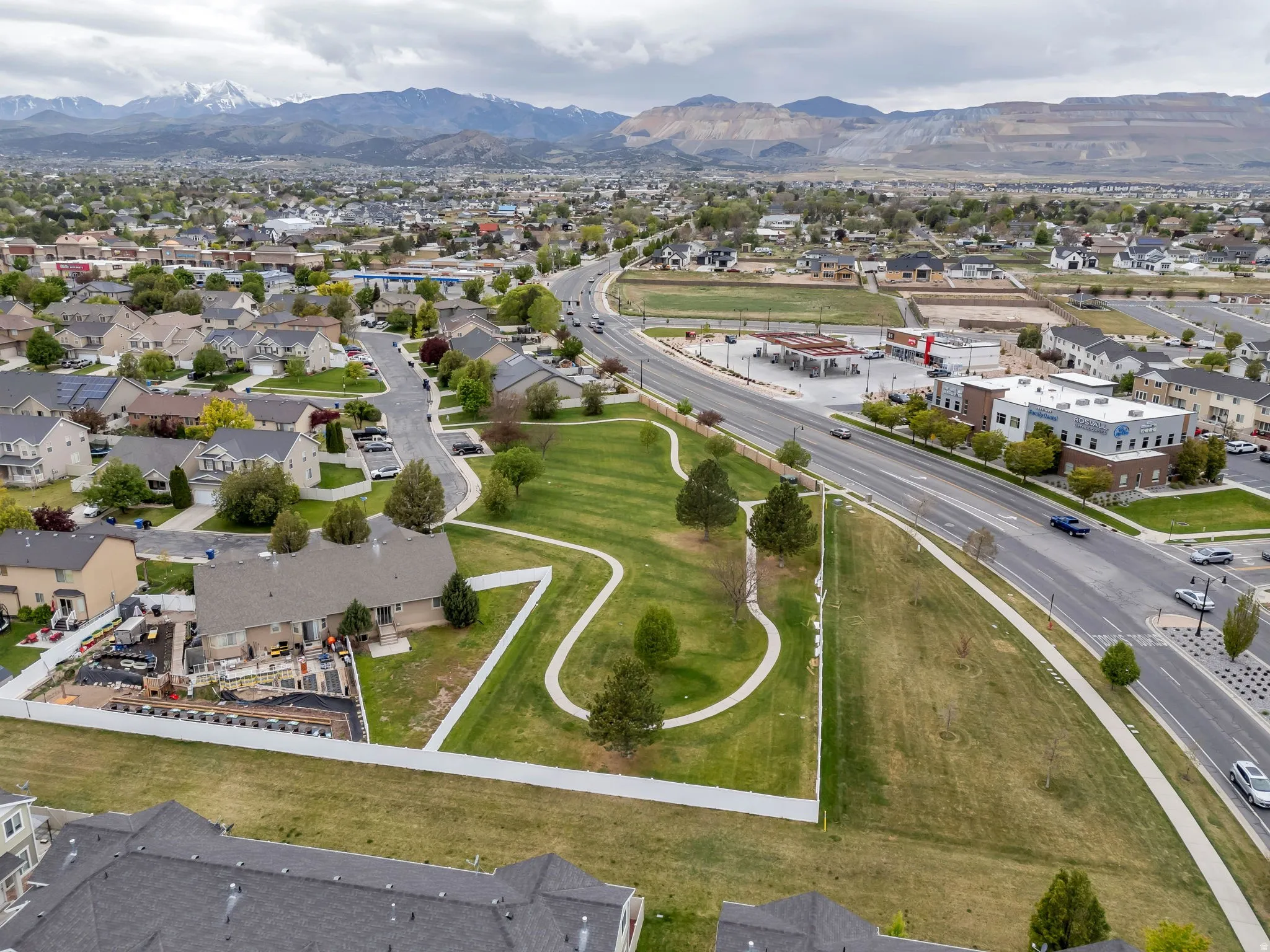 Residential neighborhood featuring a community park with walking paths, mature trees, and open green space