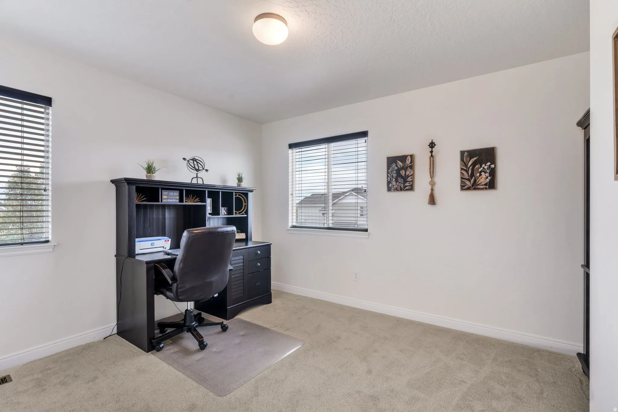 Bright room featuring two windows with horizontal blinds, neutral wall paint, and light-colored carpet flooring