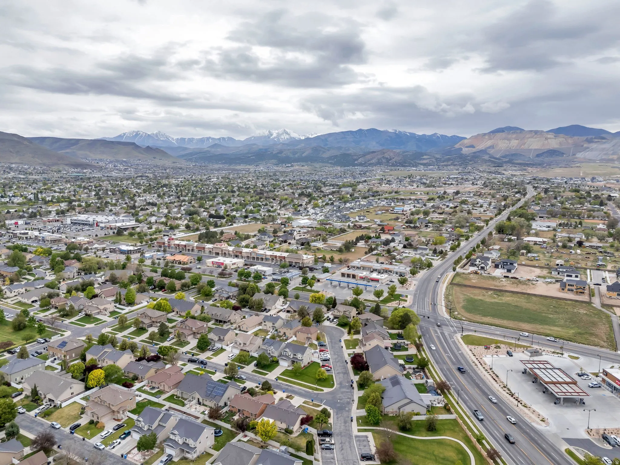 Expansive aerial view of a residential neighborhood with a backdrop of snow-capped mountains