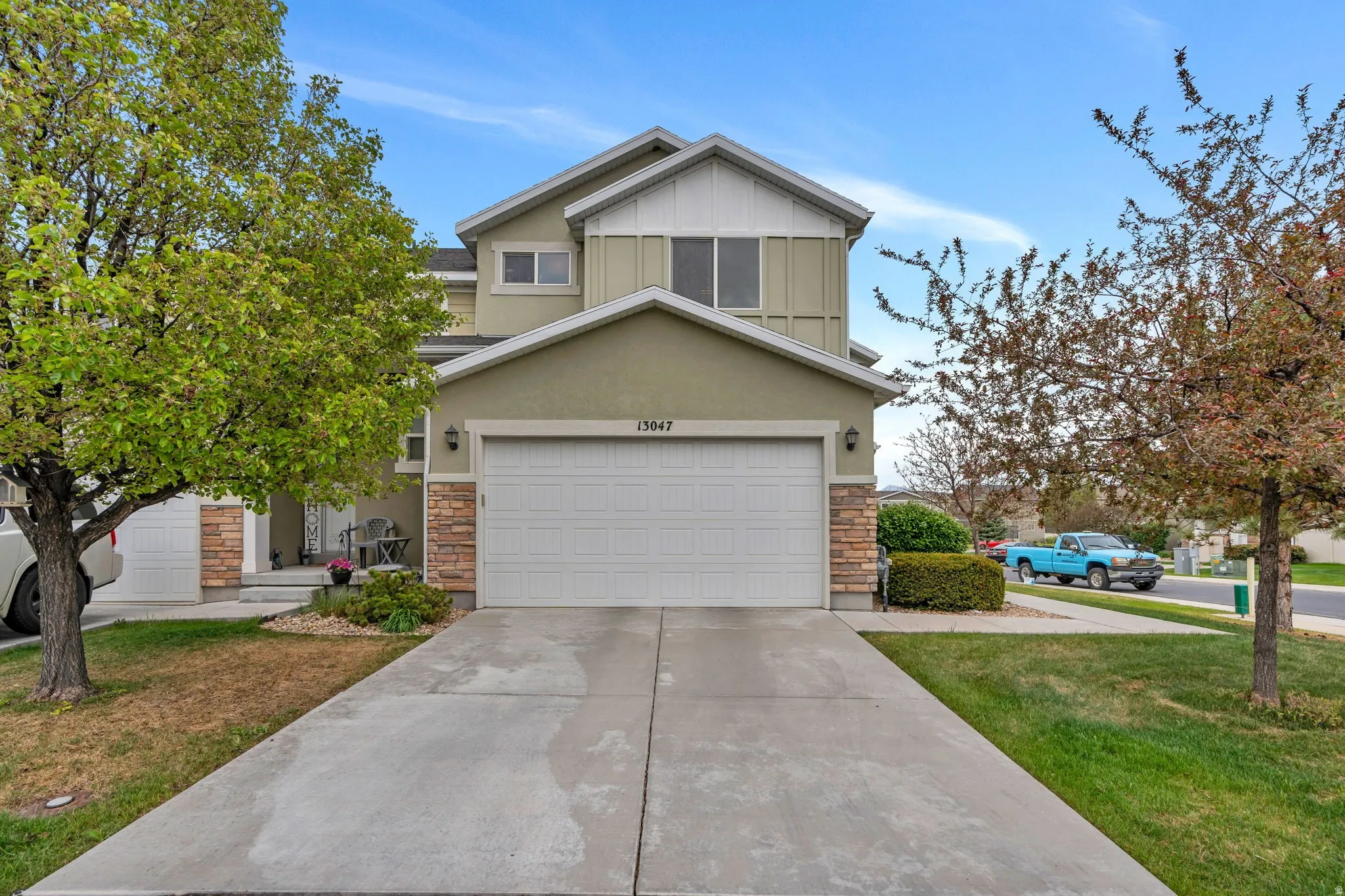 Two-story residence featuring a two-car garage, stone accents, and a concrete driveway