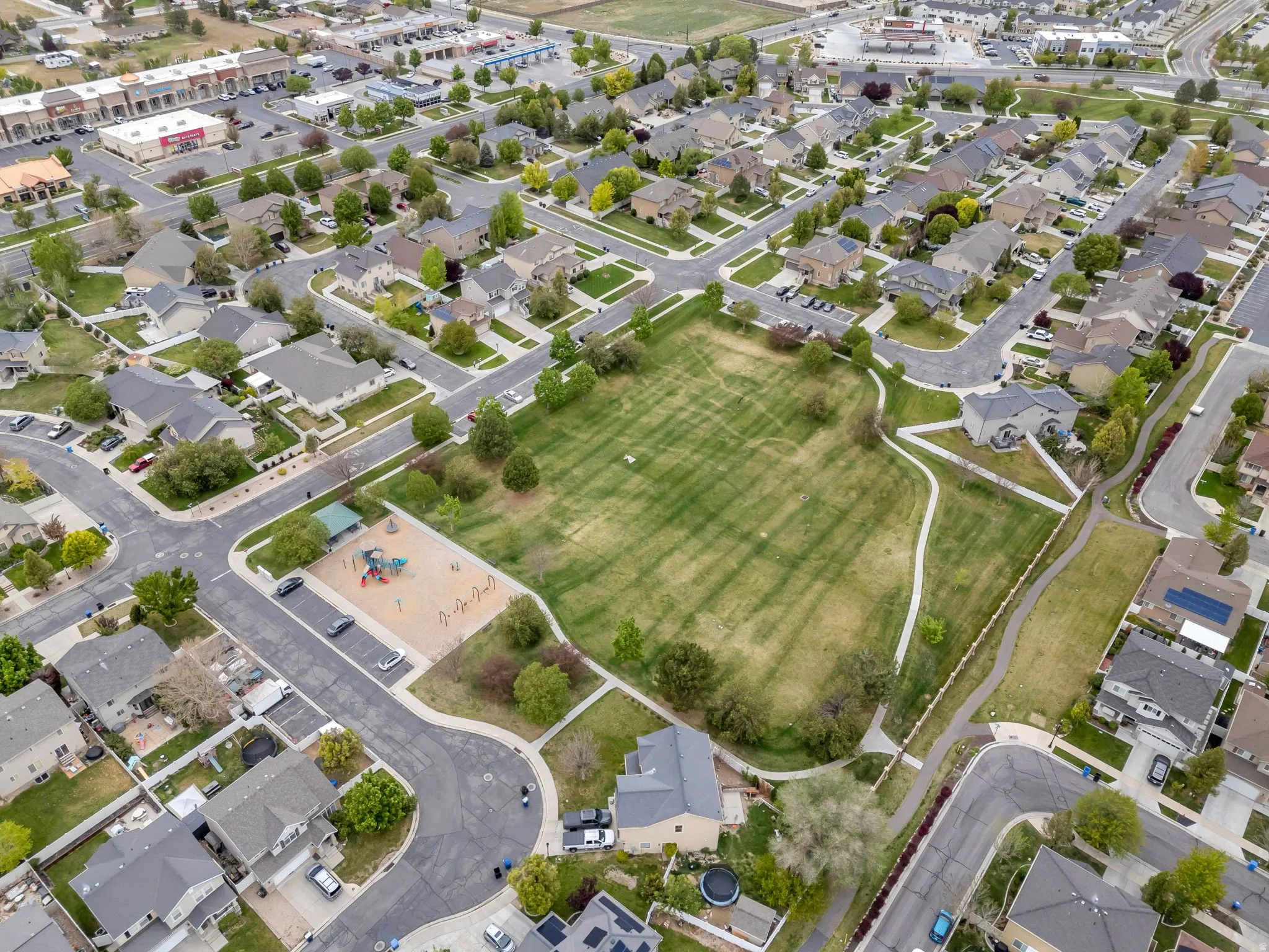 Expansive community green space with a playground, walking paths, and surrounding residential properties