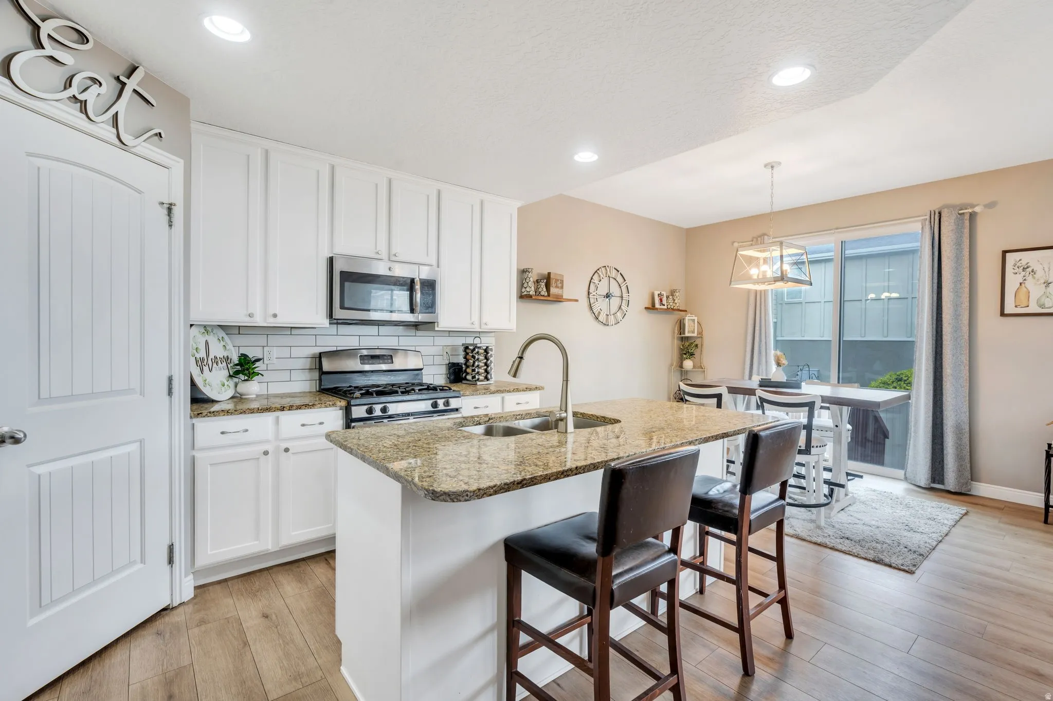 Kitchen featuring a center island with a double basin sink, stainless steel appliances, white cabinetry, and granite countertops