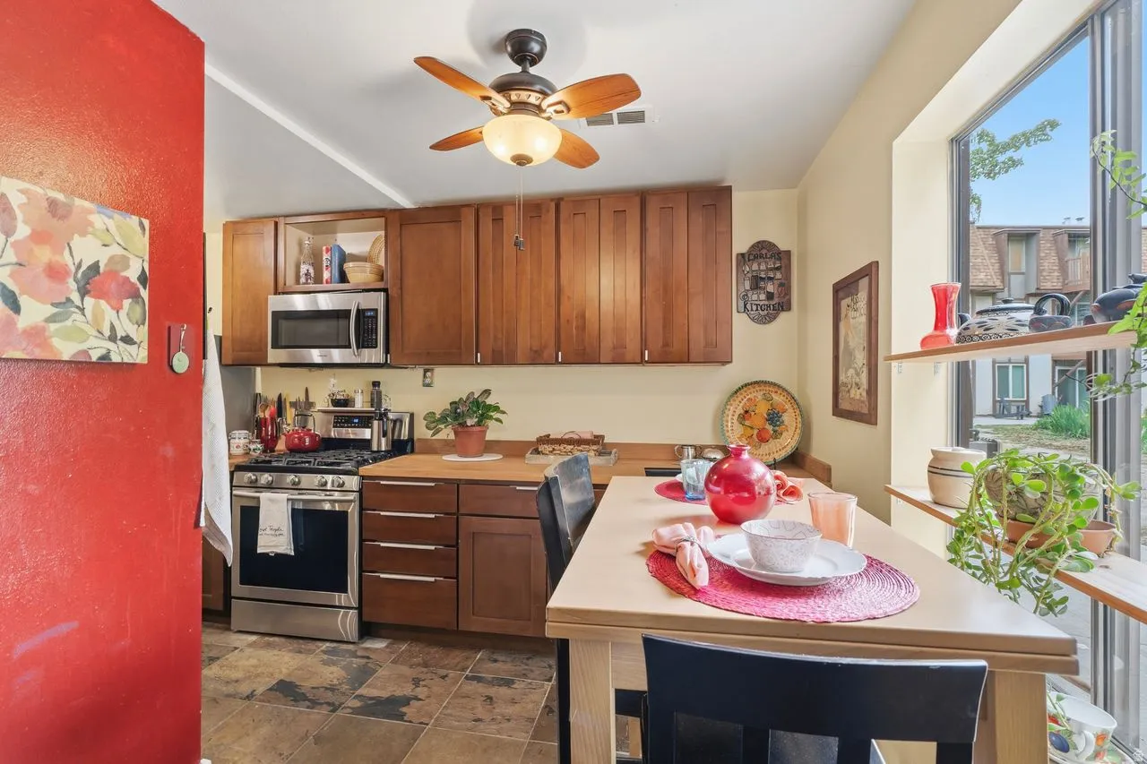 Kitchen featuring wood-finish cabinetry, stainless steel range and microwave, wood-finish countertops, and slate tile flooring that is adjacent to Dinning nook & outside oasis.
