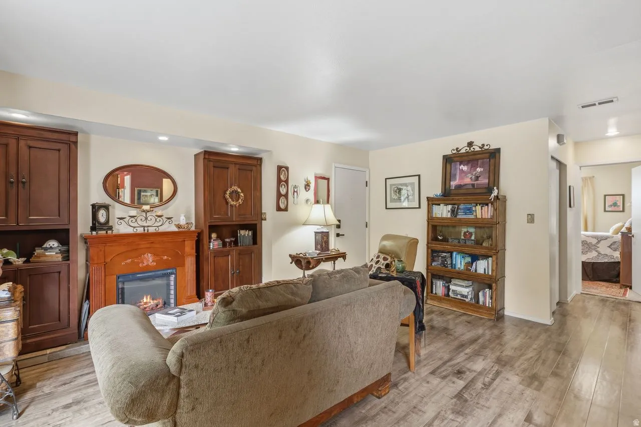 Living area featuring wood-finish flooring and a central fireplace with an ornate wood mantelpiece