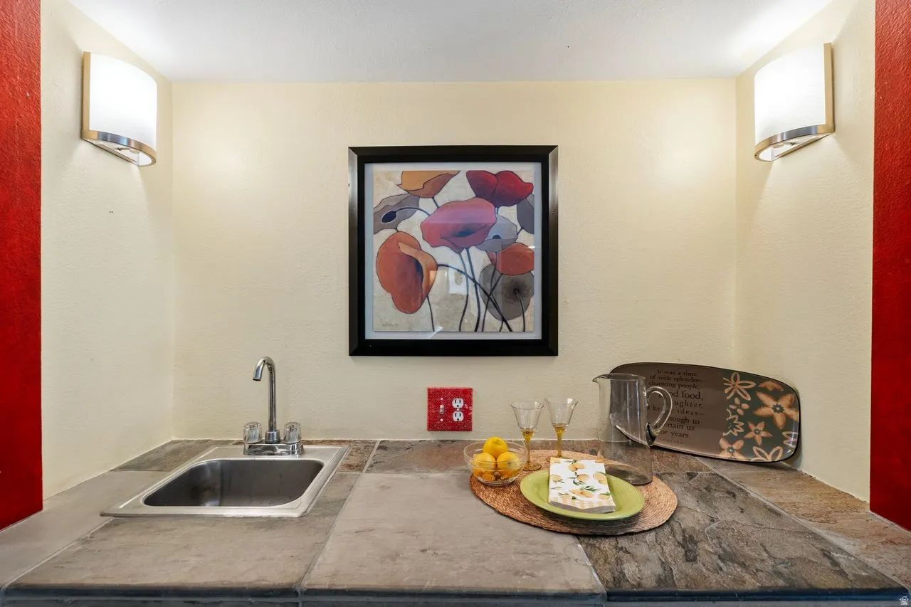A wet bar featuring a stainless steel sink, chrome faucet, and natural stone countertops. Ideal for Entertaining!