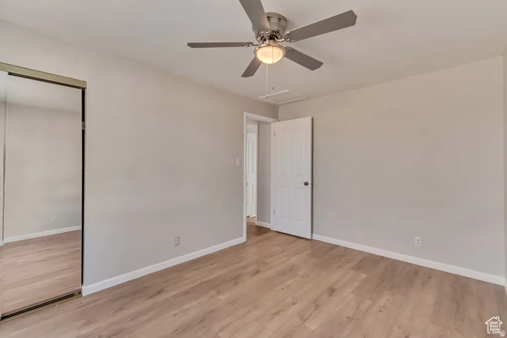 Unfurnished bedroom featuring a closet, light wood-style flooring, and ceiling fan