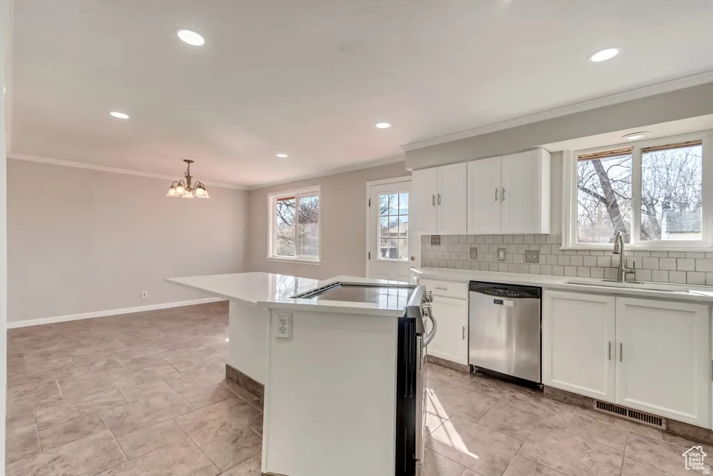 Kitchen with stainless steel appliances, tasteful backsplash, ornamental molding, white cabinets, and a center island