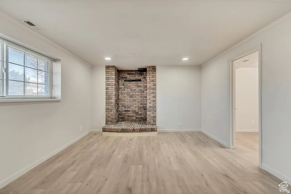 Unfurnished living room with light wood finished floors, crown molding, and recessed lighting