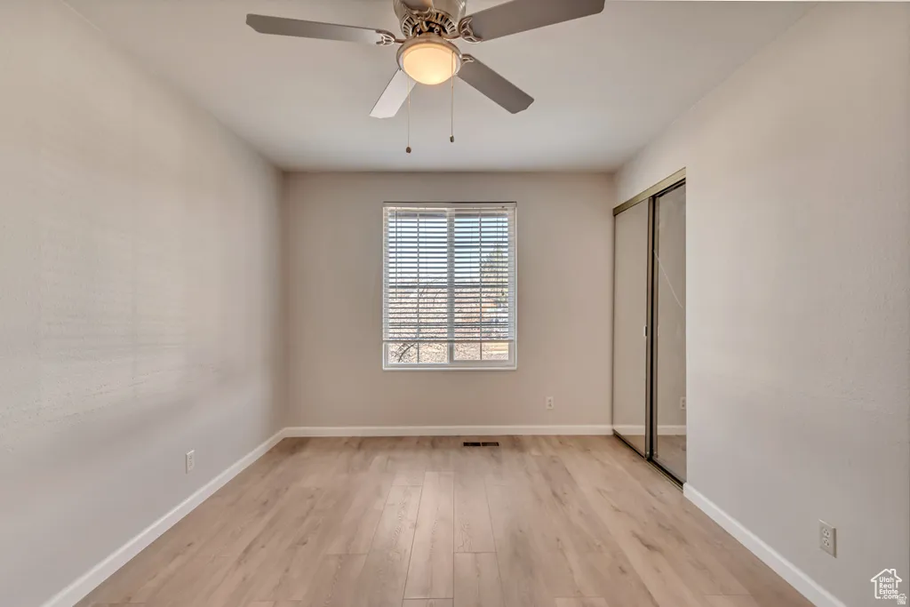 Unfurnished bedroom featuring light wood-style floors, a closet, and ceiling fan