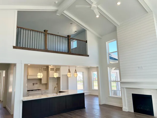 Two-story living area featuring a vaulted ceiling with exposed beams, a ceiling fan, and recessed lighting