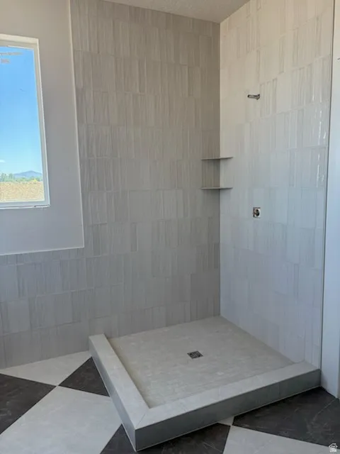 Walk-in shower with vertical stacked tile, built-in corner shelving, and a tiled shower pan