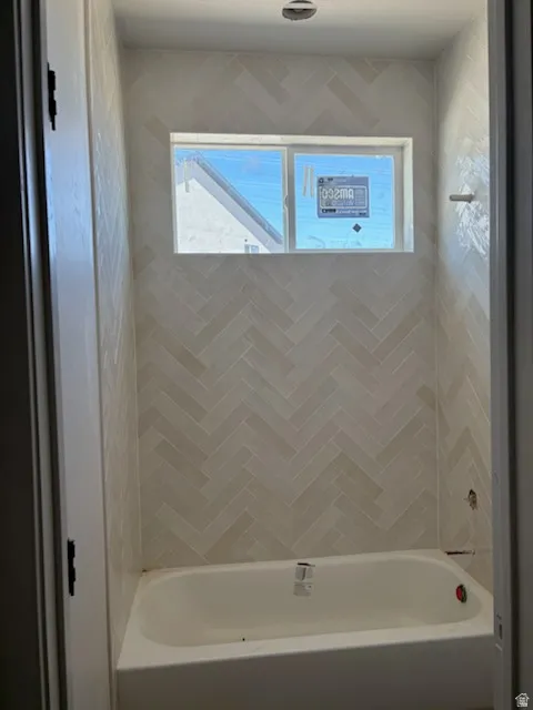 Bathtub and shower surround featuring a herringbone tile pattern