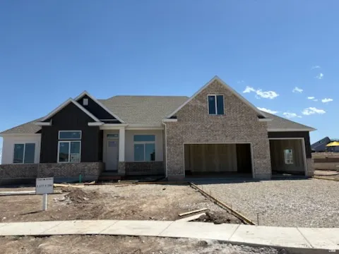 Newly constructed residence featuring a blend of light brick veneer and dark vertical siding