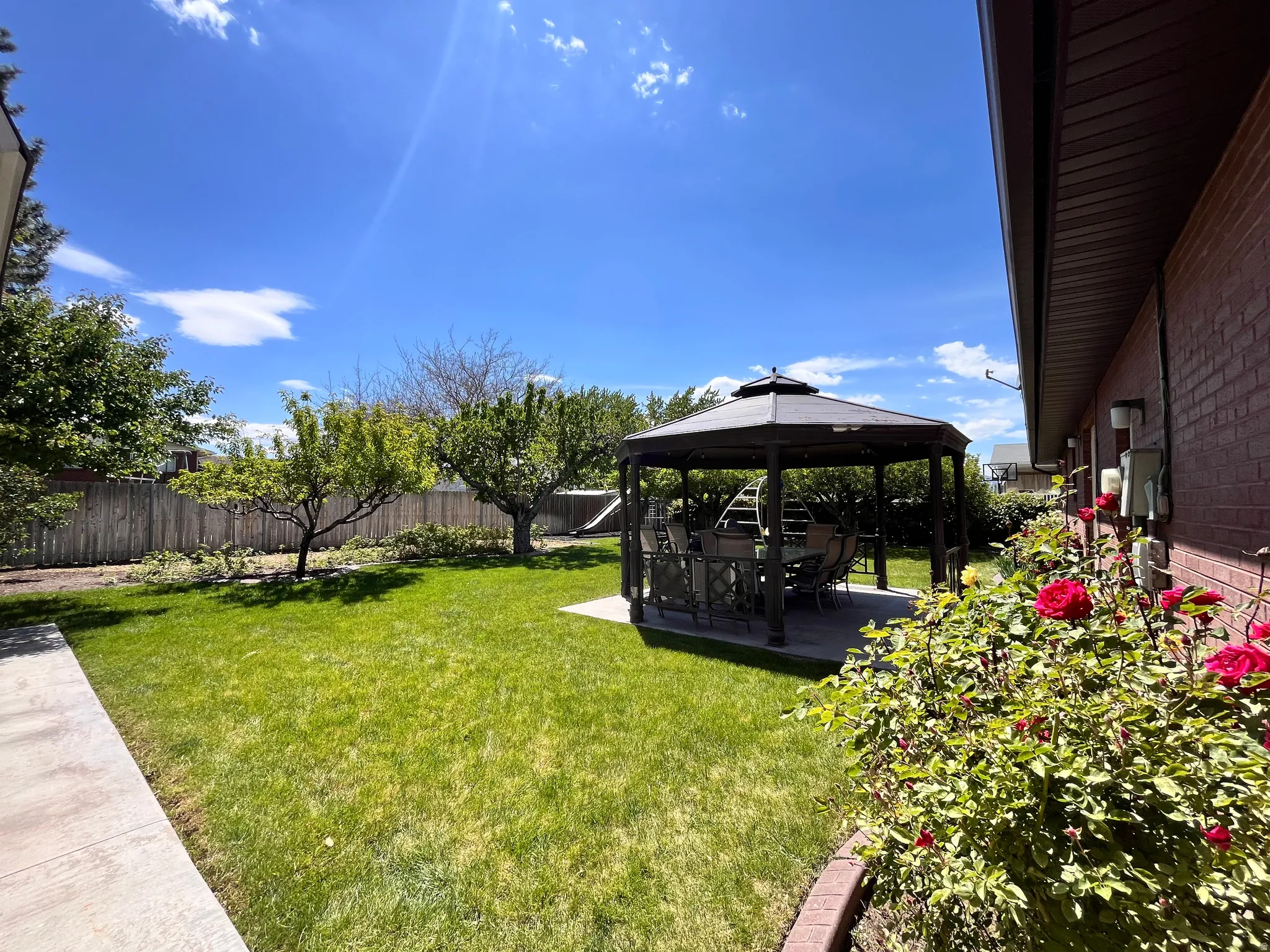 Expansive backyard with a manicured lawn, established trees, and a concrete patio