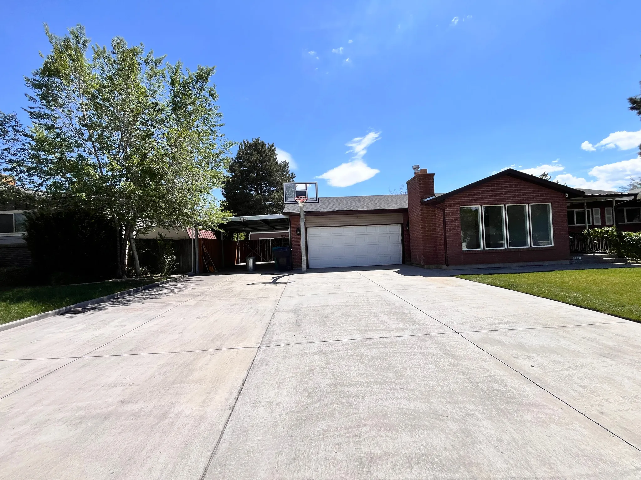 Brick exterior with a prominent chimney, a two-car garage, and a long concrete driveway