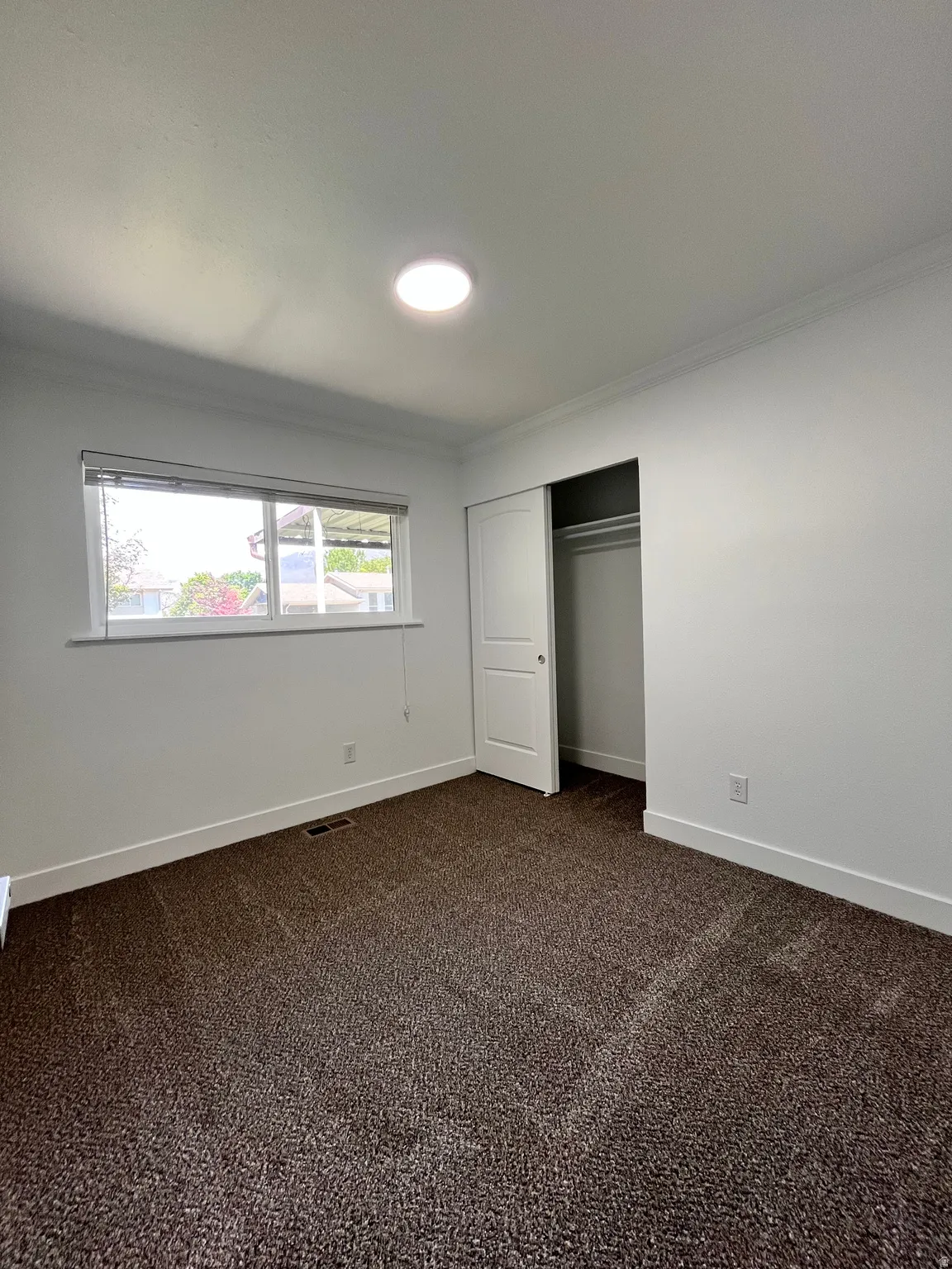 Room featuring a window with blinds, recessed ceiling lighting, crown molding, and neutral-toned carpeting