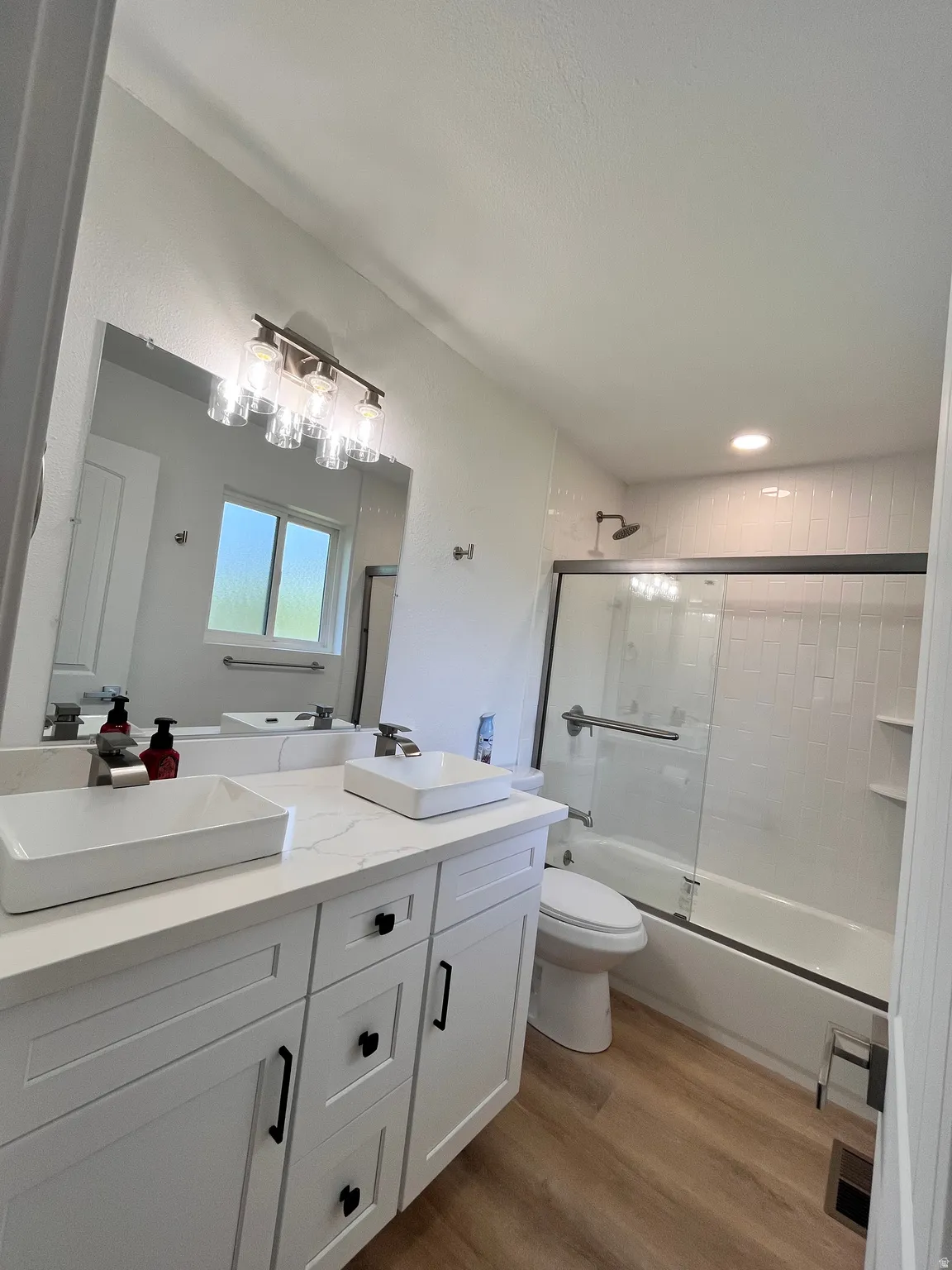 Bathroom featuring a double vanity with vessel sinks, white cabinetry, and a quartz countertop
