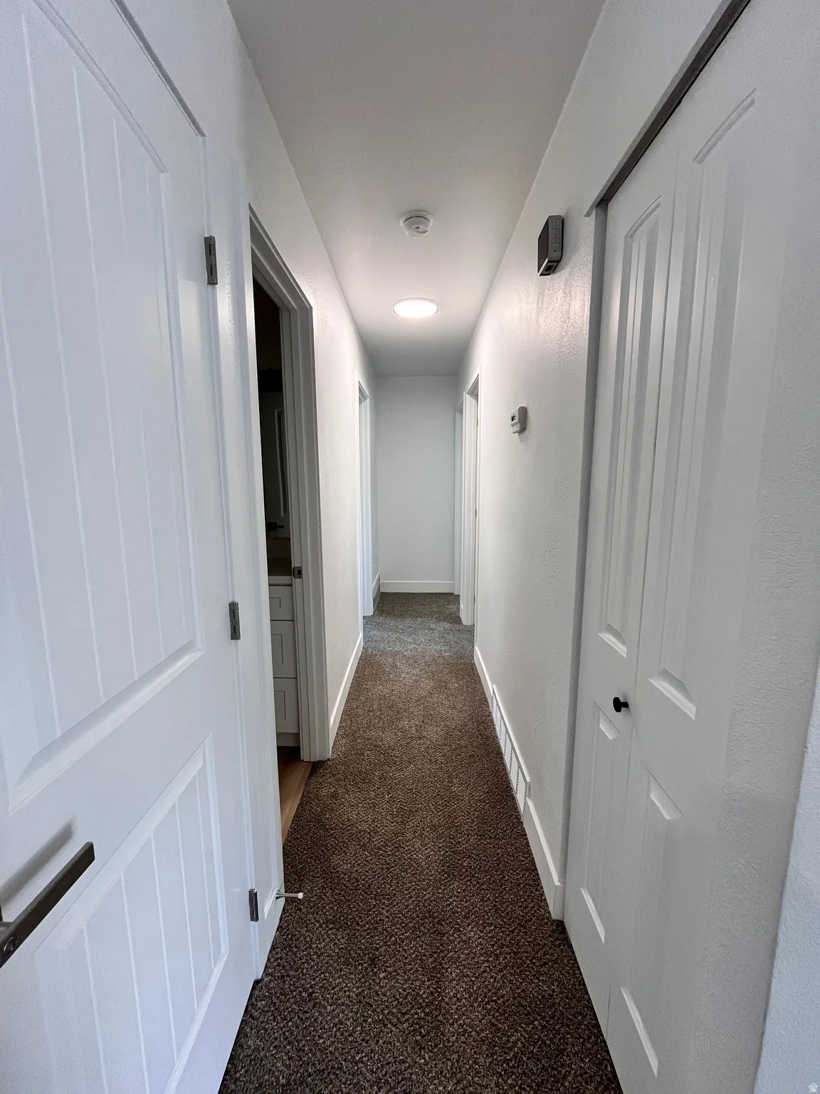 Hallway featuring brown textured carpeting, white walls, and recessed lighting