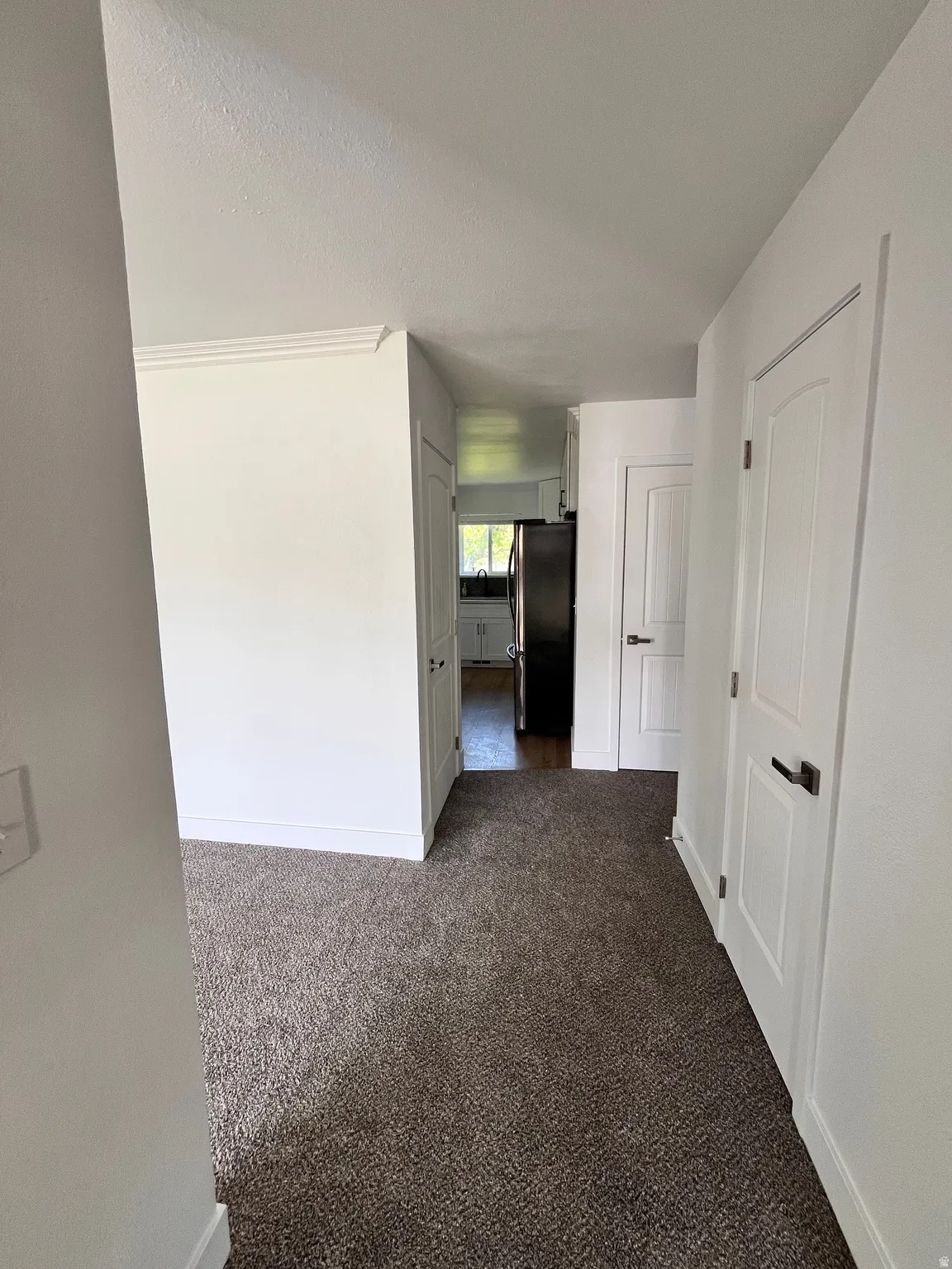 Carpeted entryway with white baseboards and crown molding