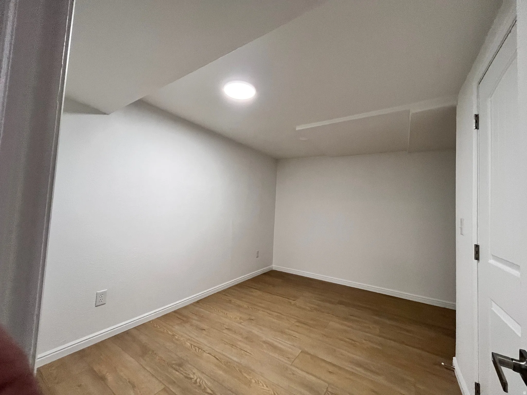 Room featuring light wood-finish flooring, white walls, white baseboards, and a recessed ceiling light