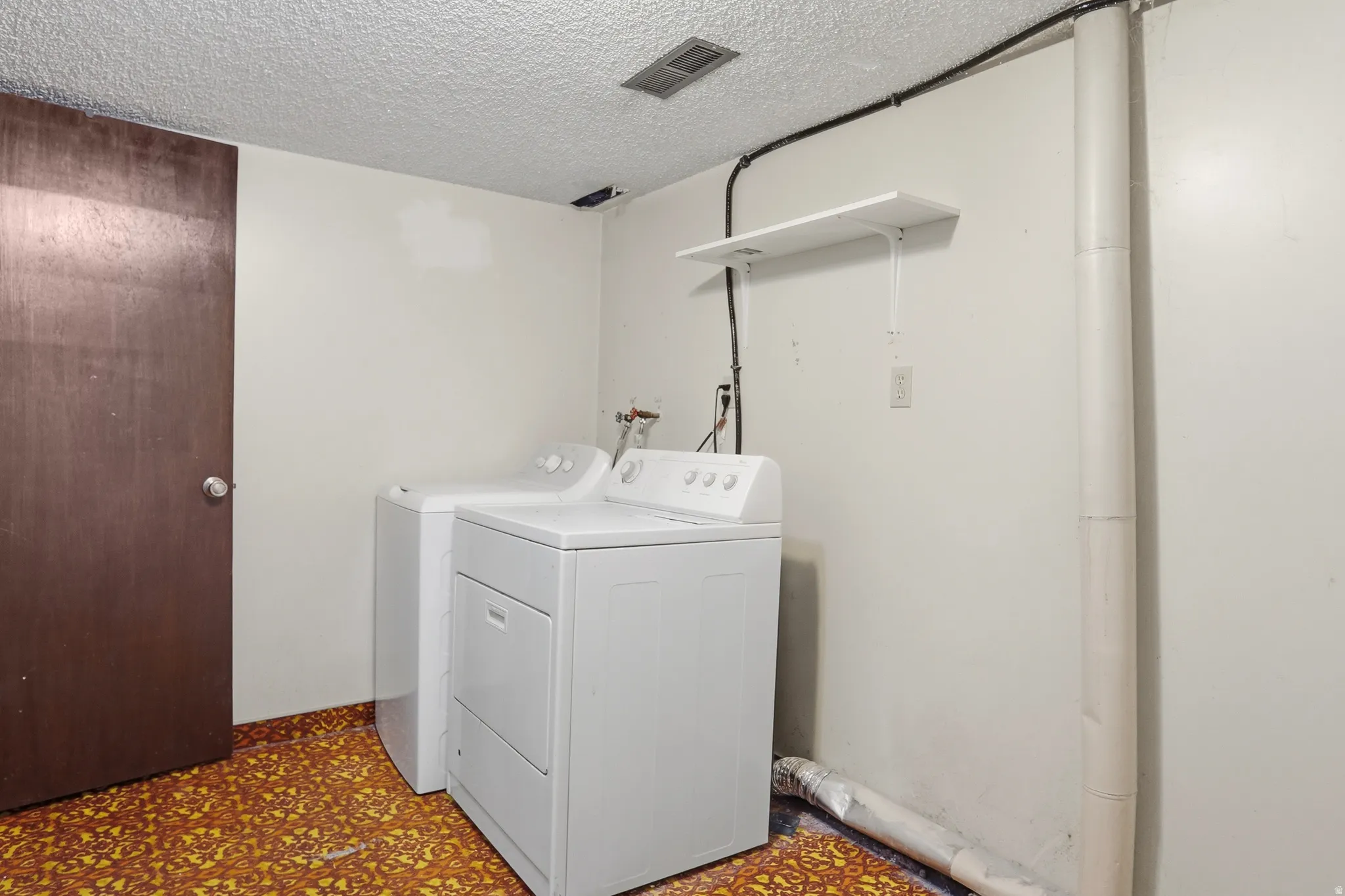 Dedicated laundry area featuring a washer and dryer, textured ceiling, and a dark wood-finish door