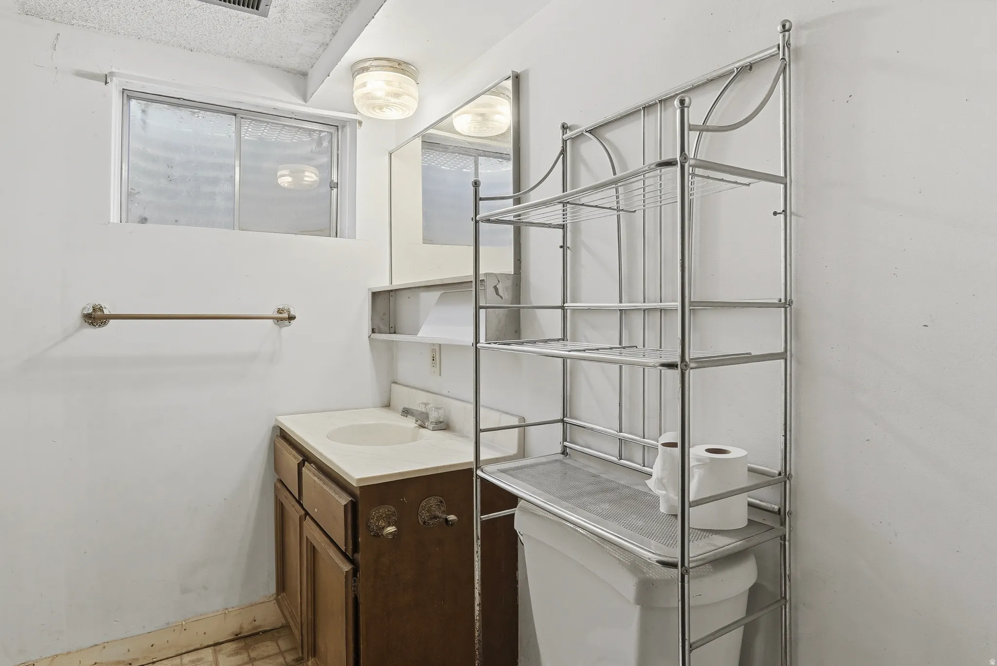 Bathroom featuring a single vanity with a laminate countertop, an integrated sink, and a built-in medicine cabinet