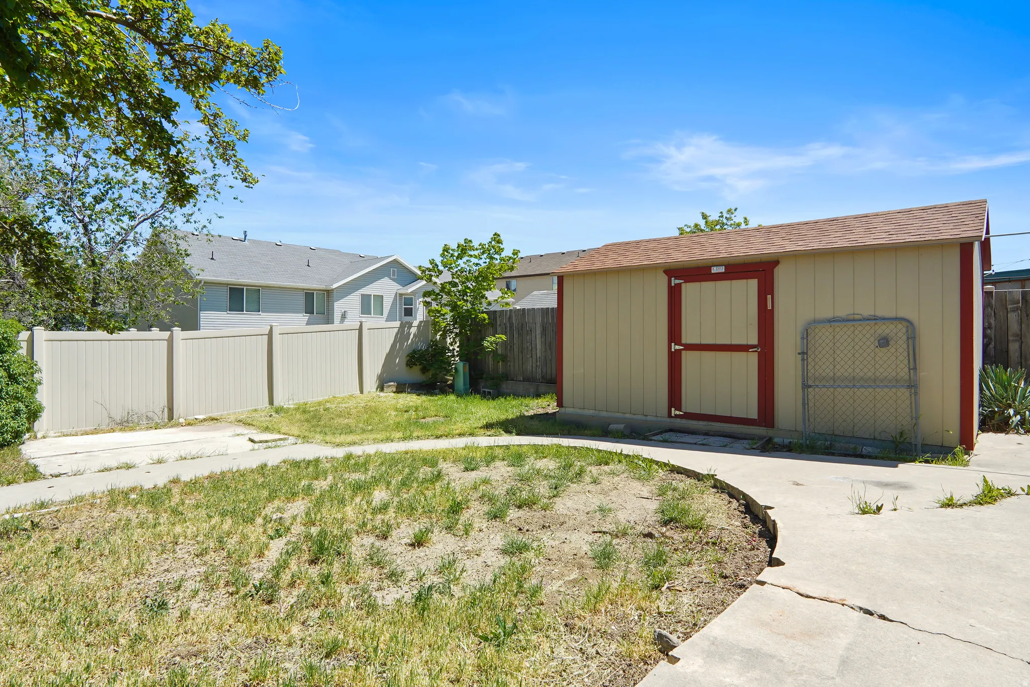 Spacious backyard featuring a storage shed with a brown shingle roof and red trim