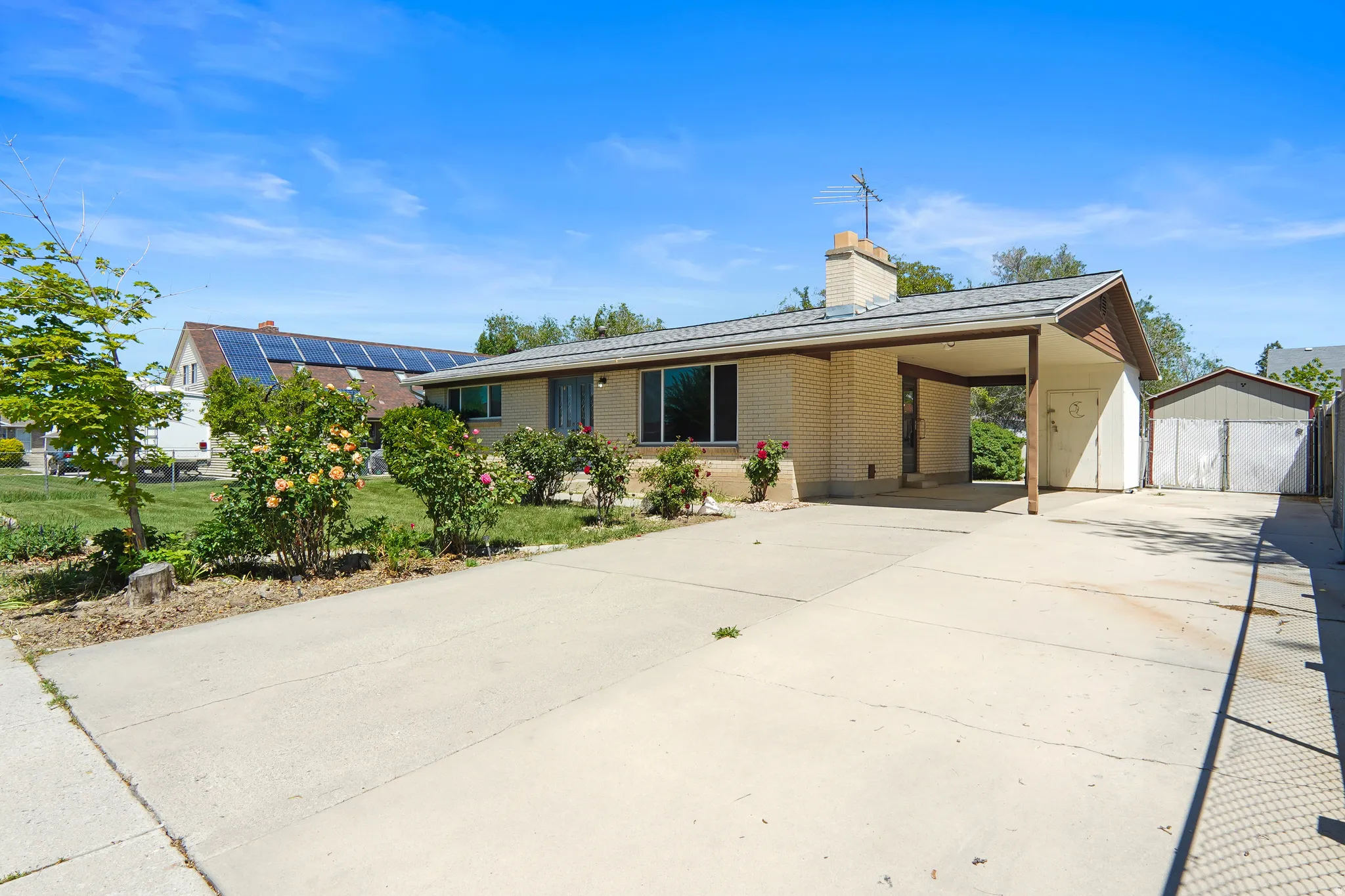 Single-story brick exterior with an attached carport, an extended concrete driveway, and a detached two-car garage