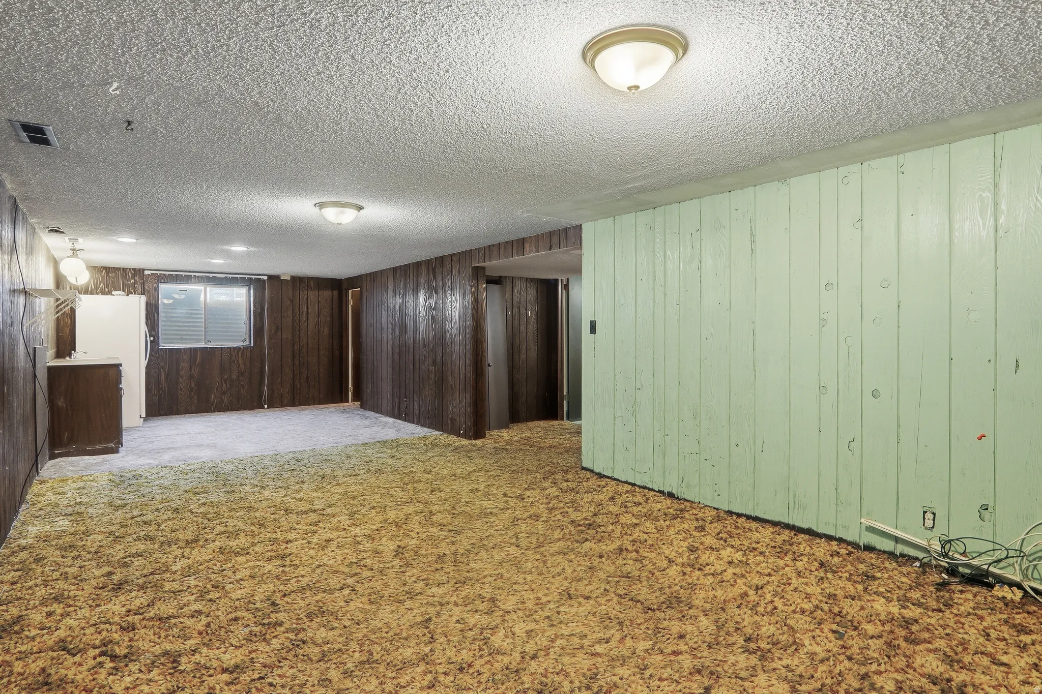 Spacious room featuring textured ceiling, recessed lighting, and a window with blinds