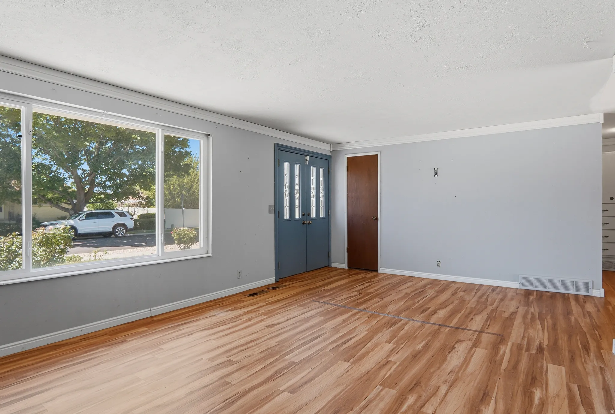 Spacious room featuring wood-finish flooring, light grey walls, and white trim
