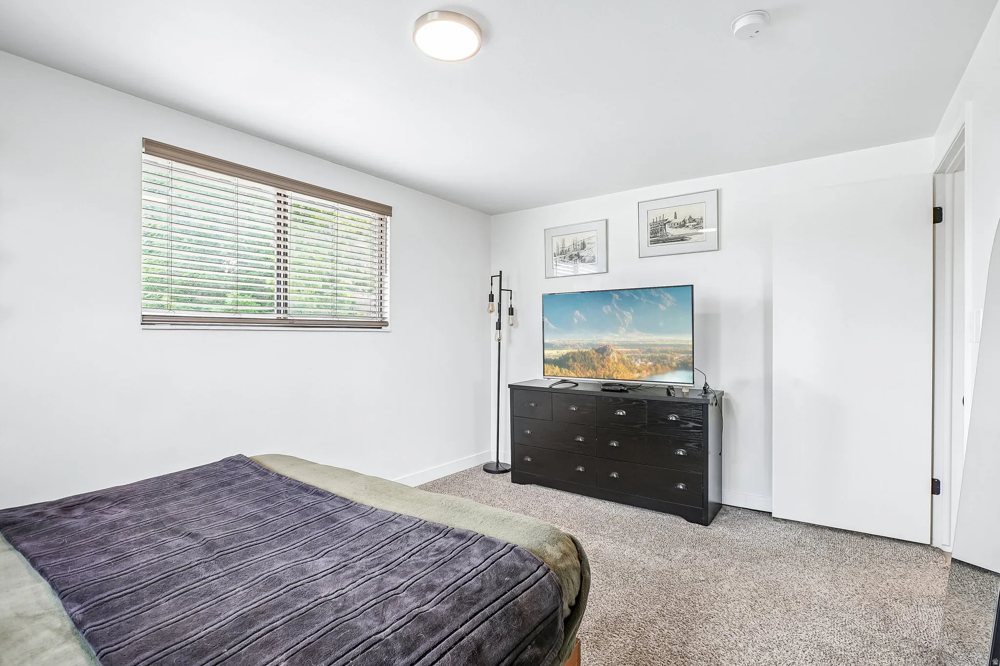 Carpeted room featuring a single window with horizontal blinds, white walls, and a flush-mount ceiling light