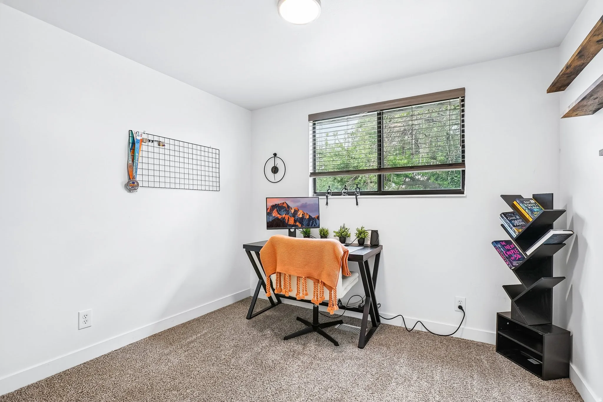 Carpeted room featuring a large window with blinds, white walls, and a ceiling light fixture