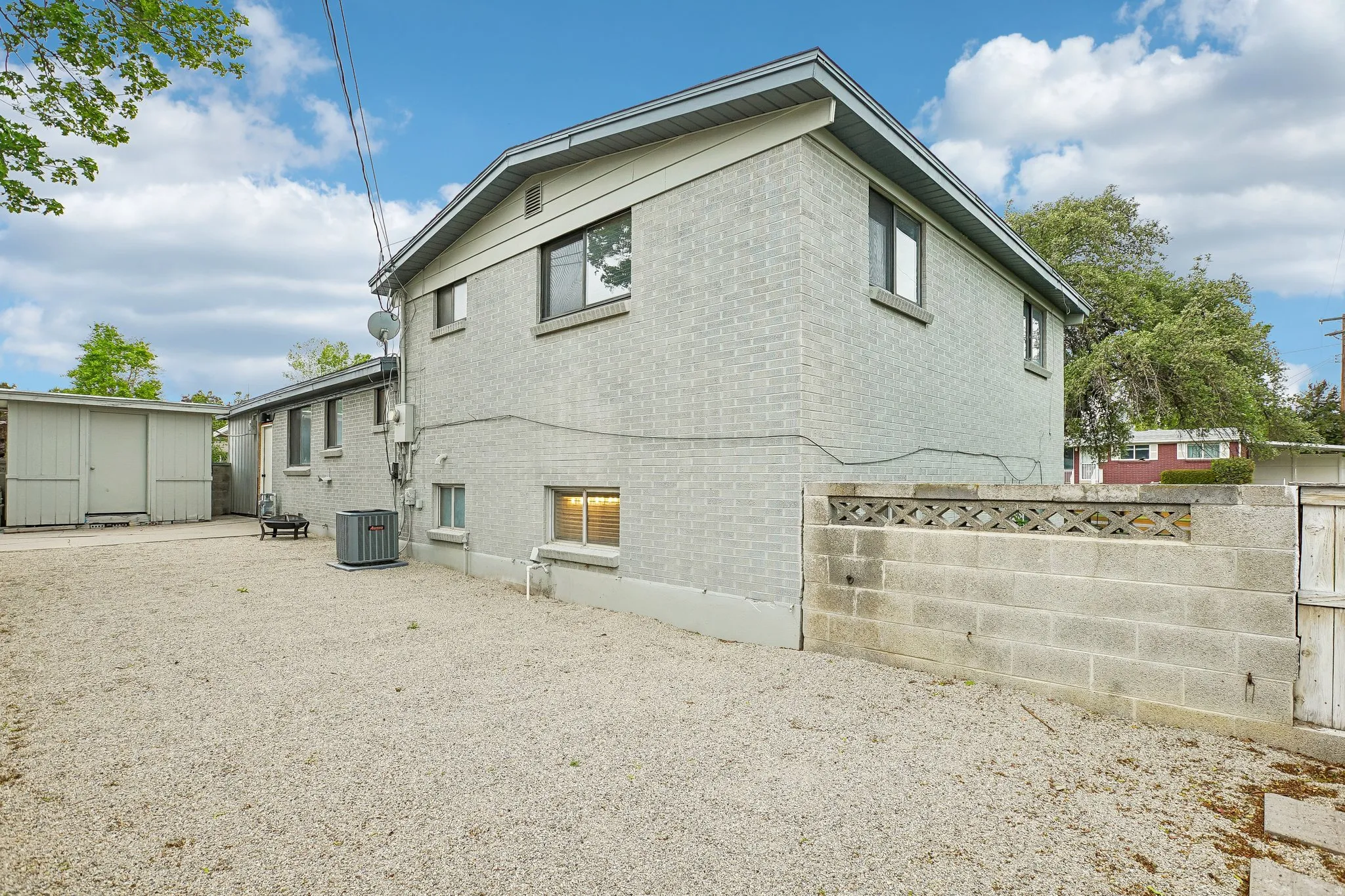Rear exterior featuring light grey brick siding and a low-pitched roofline