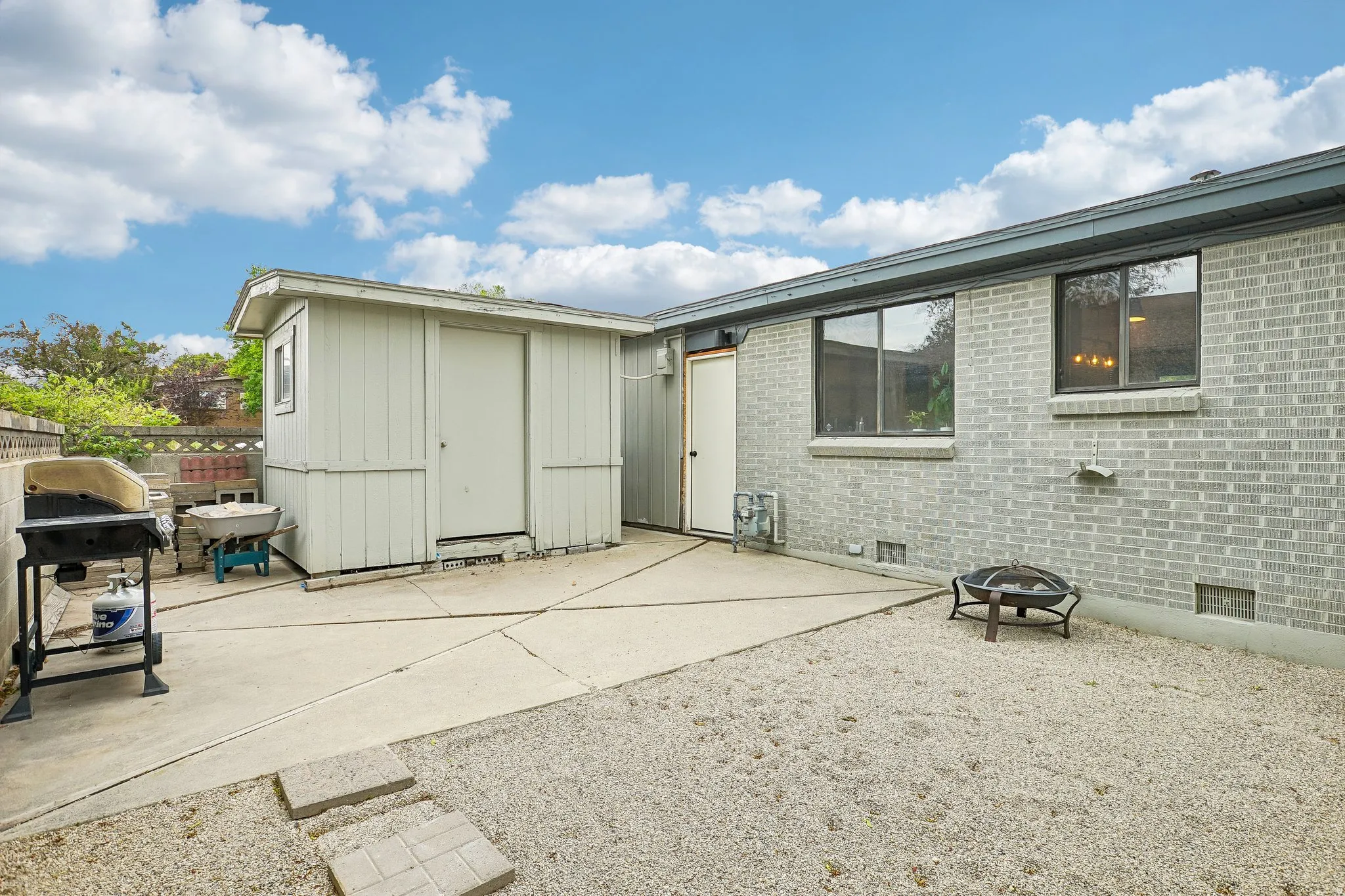 Expansive outdoor space featuring a concrete patio, pea gravel area, and a detached storage shed