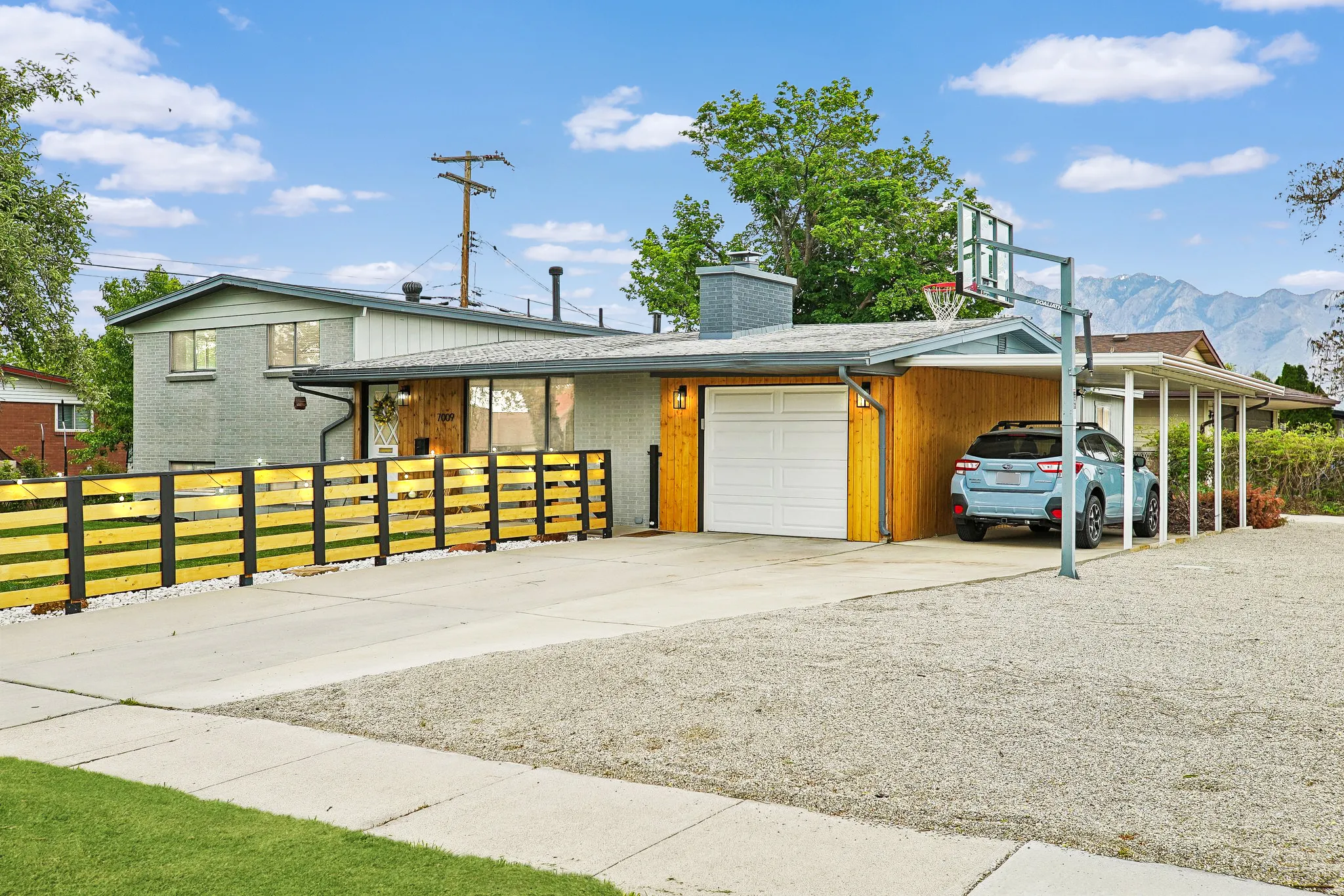 Exterior features a horizontal slat fence, an attached garage with a white door, and an open carport