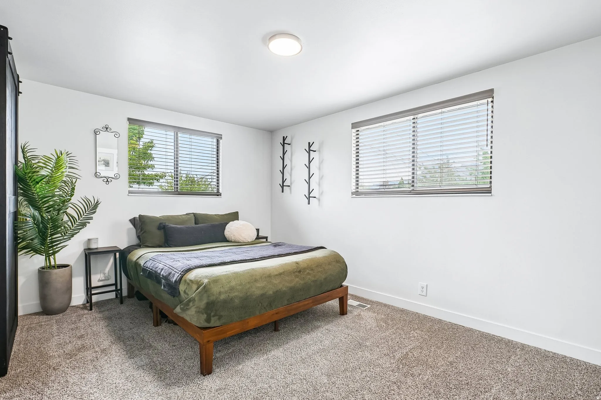 Carpeted room with a ceiling-mounted light fixture and two windows featuring blinds